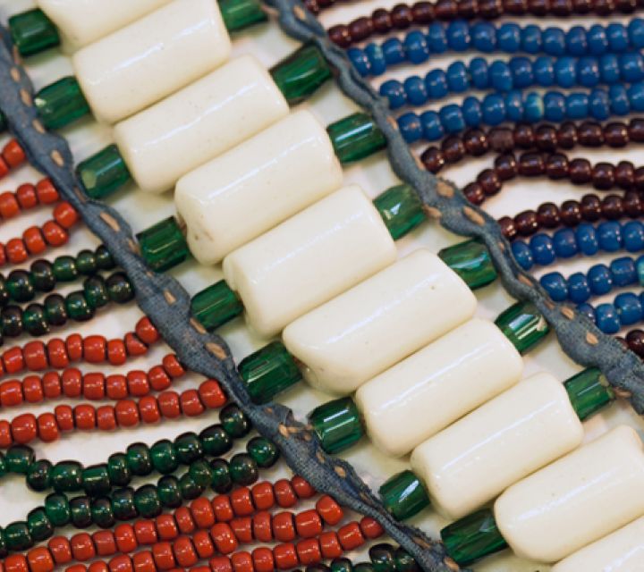 detail of historic beaded headdress with rosa of colorful beads between leather strips.