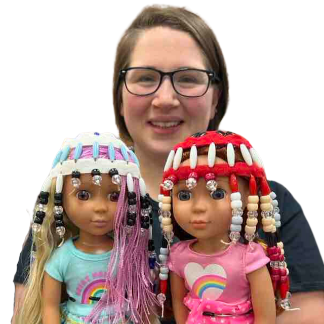 Woman holding two dolls, each with beaded headdress.