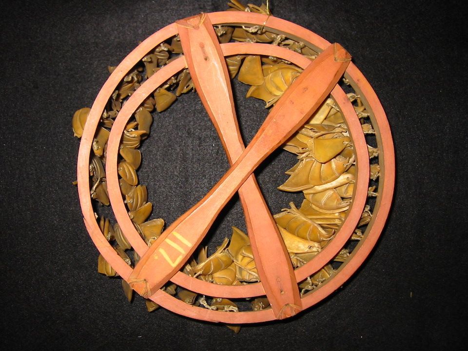 Drawing of a puffing beak rattle, with beaks lashed to two circular hoops, ties to a long narrow handle.