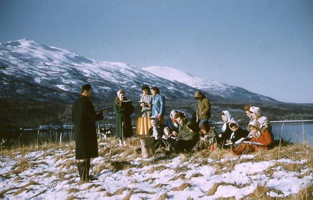 Pastor standing in snow speaking to a group of people.